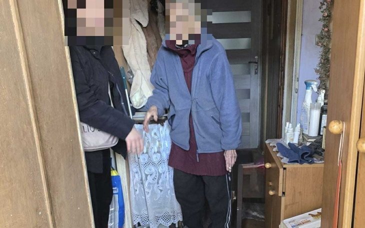 Dwie osoby w drzwiach, jedna z nich trzyma laskę.