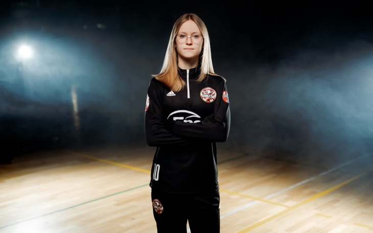 Młoda zawodniczka w czarnym stroju sportowym na boisku z planem do fotografii