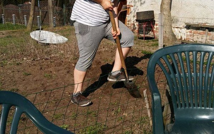 Osoba kopie ziemię w ogrodzie, trzyma łopatę.