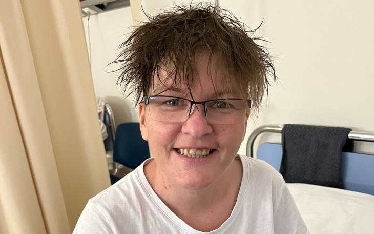 Kobieta z nietypową fryzurą uśmiecha się do kamery.