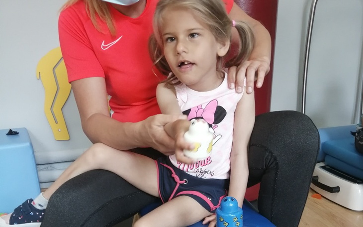 Mała dziewczynka siedzi na kolanach terapeuty.