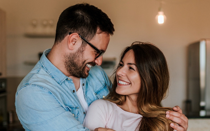Szczęśliwa para uśmiechająca się do siebie w przytulnym wnętrzu.