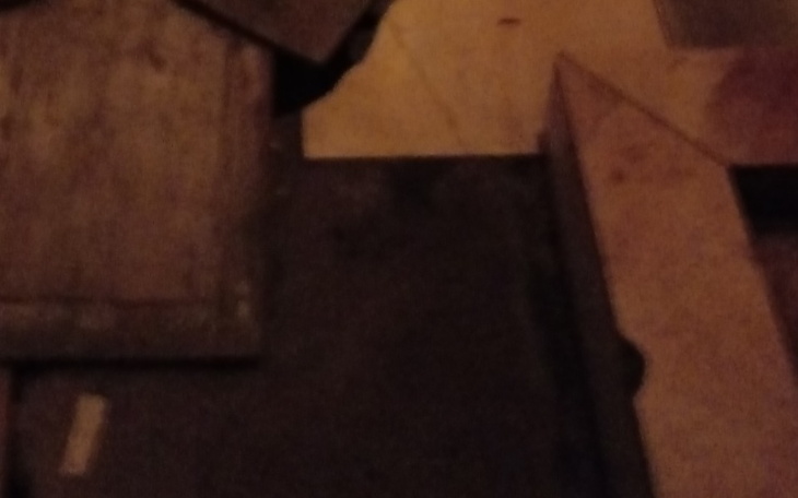 Zniszczona podłoga w ciemnym pomieszczeniu, z widocznymi fragmentami drewna.