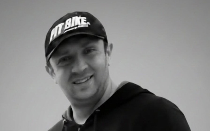 Mężczyzna w czapce uśmiechający się do kamery.