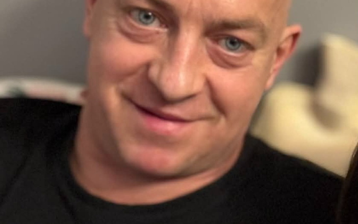 Mężczyzna z uśmiechem, siedzący na kanapie.