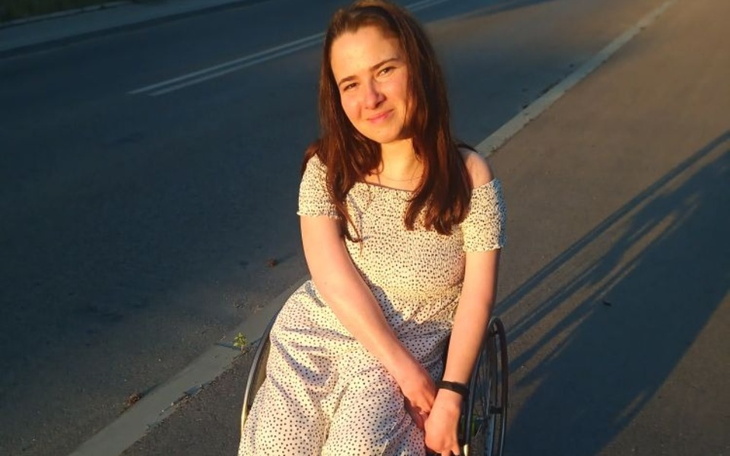 Młoda kobieta w białej sukience na wózku inwalidzkim.