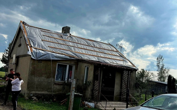 Dom z uszkodzoną dachówką, zabezpieczony folią.