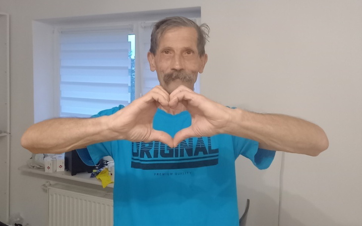 Mężczyzna w niebieskiej koszulce, robiący znak serca.