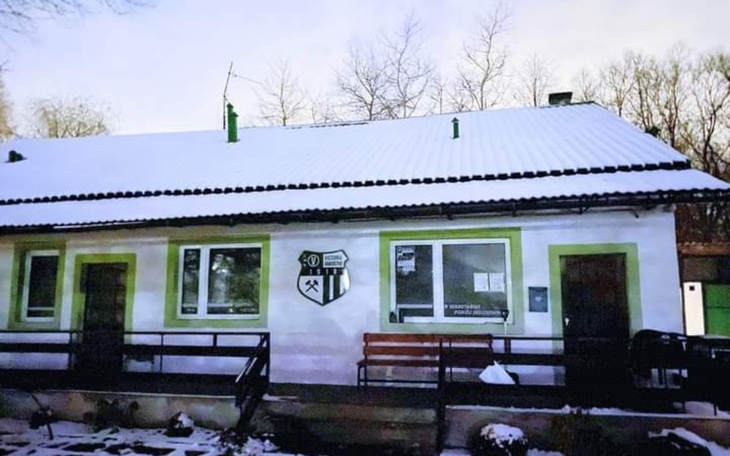 Zimowy widok na dom z zielonymi akcentami.