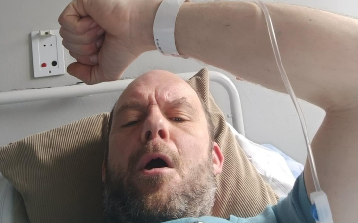 Mężczyzna w szpitalu, trzymający rękę z opaską.