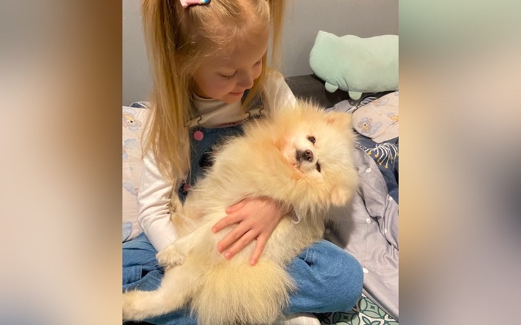 Dziewczynka przytulająca pomeraniana na kanapie.