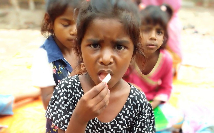 Dziewczynka z wyrazem twarzy skupienia, trzymająca coś w ustach.
