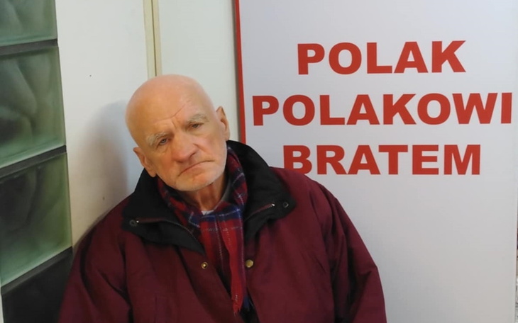 Starszy mężczyzna siedzący obok napisu 'Polak Polakowi Bratem'.