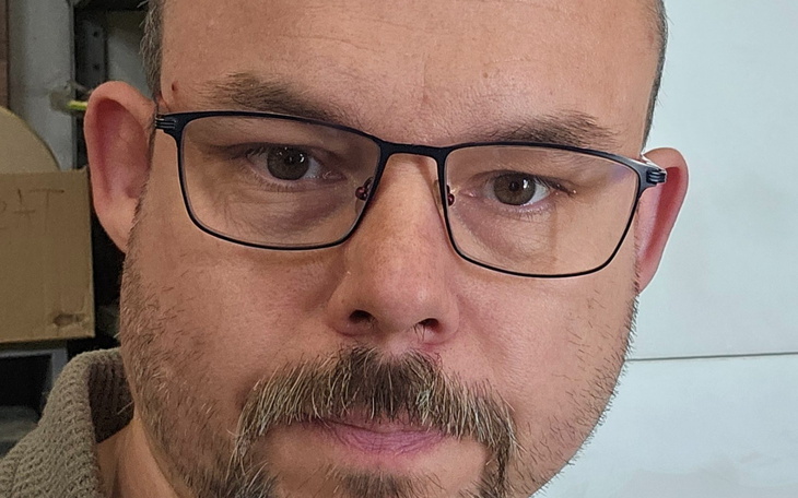 Mężczyzna w okularach, z poważnym wyrazem twarzy.