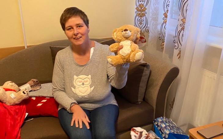 Kobieta trzymająca pluszowego misia w salonie.