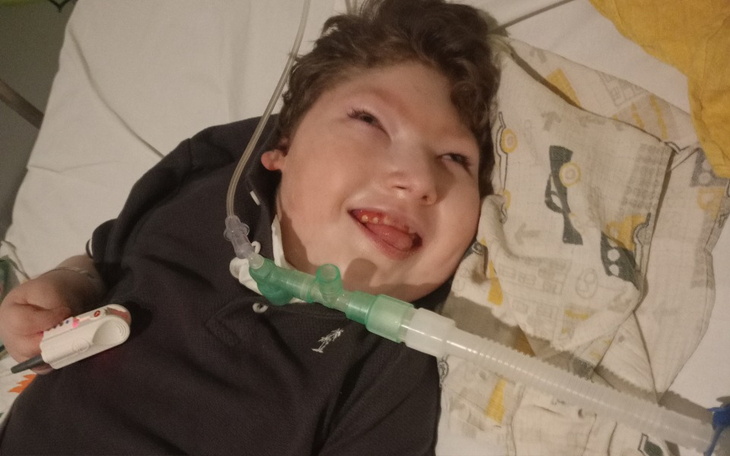 Chłopiec z uśmiechem, leżący w łóżku szpitalnym.