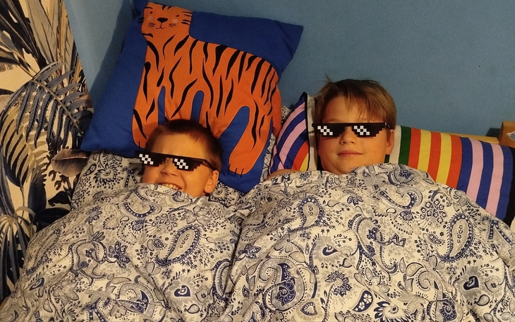 Dwóch chłopców w okularach przeciwsłonecznych, przykrytych kocem.