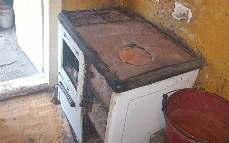 Stara kuchenka gazowa w zaniedbanym pomieszczeniu.