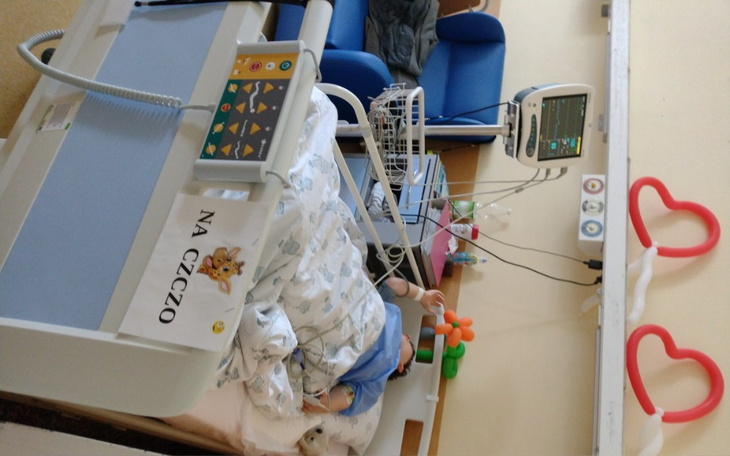 Dziecko w szpitalnym łóżku, otoczone troską i opieką.