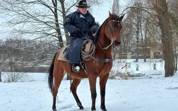 Mężczyzna na koniu w zimowym krajobrazie.