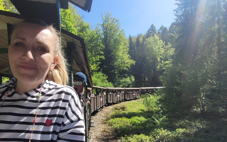 Kobieta w lesie, uśmiechająca się podczas jazdy pociągiem.