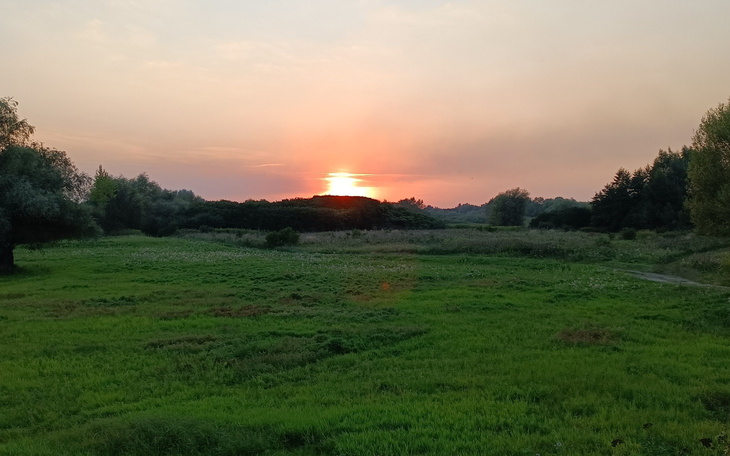 Zachód słońca nad zielonymi łąkami, piękne widoki natury.