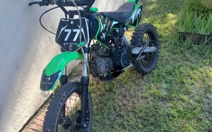 Motocykl terenowy zaparkowany na trawie.