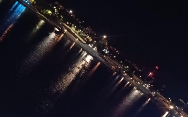 Widok na oświetloną promenadę nad wodą w nocy.