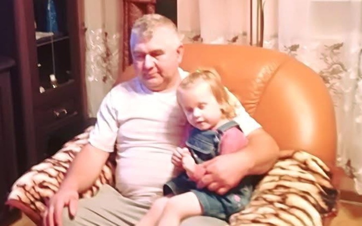 Dziecko siedzące na kolanach dziadka w przytulnym fotelu.