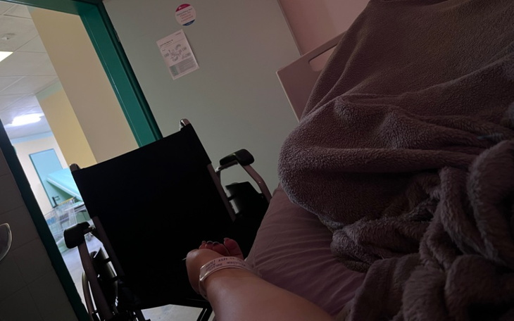 Osoba w szpitalu, widok na rękę i wózek inwalidzki.