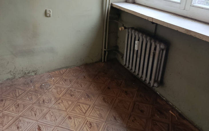 Zniszczony kąt w pomieszczeniu z grzejnikiem i podłogą.