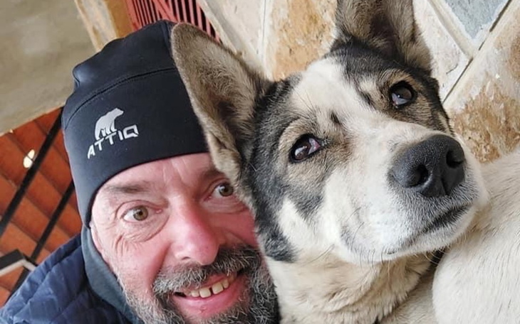 Mężczyzna z psem, obaj uśmiechnięci i zrelaksowani.