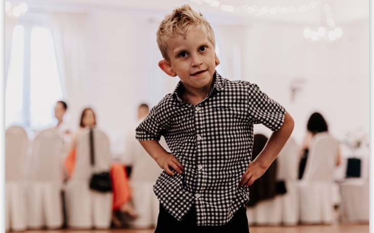 Chłopiec w kratkowanej koszuli, pozujący na imprezie.