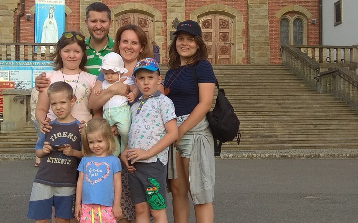 Rodzina pozująca do zdjęcia przed budynkiem.