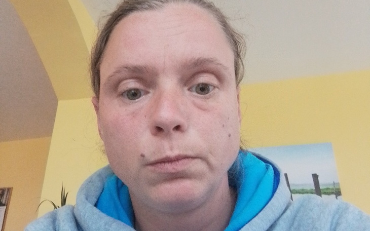 Kobieta z zamyśloną miną, siedząca w jasnym pomieszczeniu.