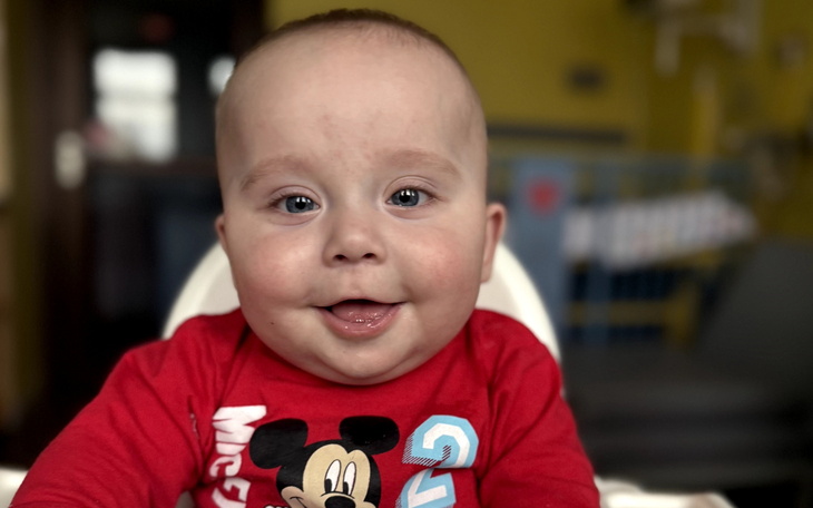 Uśmiechnięty niemowlak w czerwonym body z Mikiem Mousem.