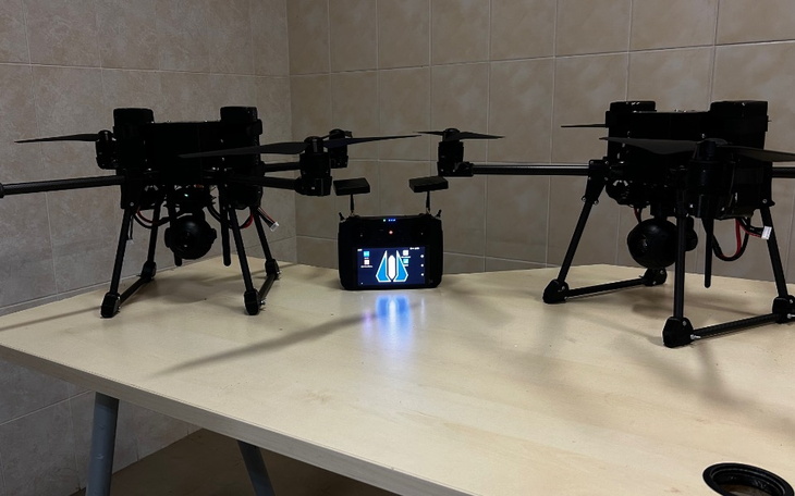 Dwa drony na stole, z wyświetlaczem w centrum.