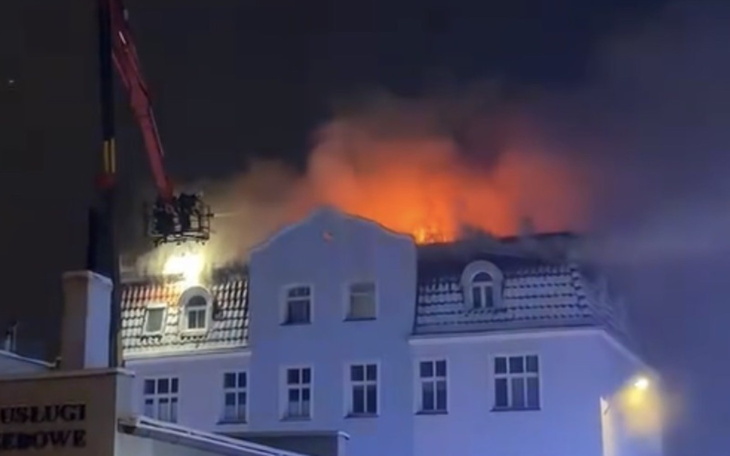 Pożar na dachu budynku, widać ogień i dym.