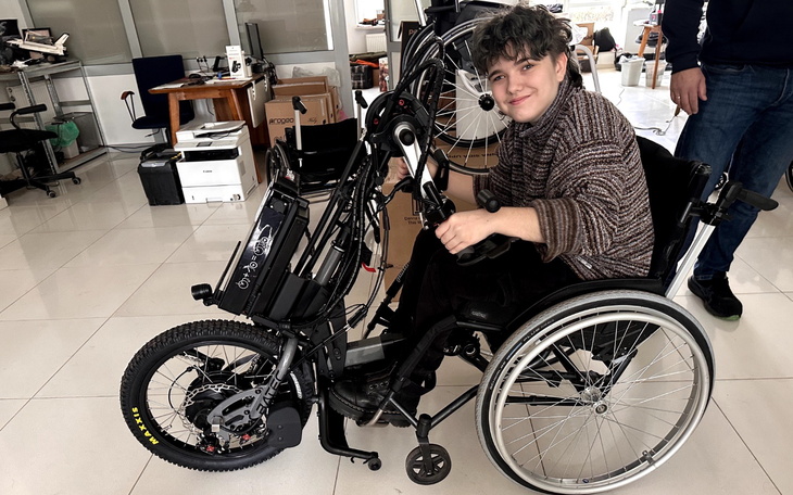 Młody mężczyzna w wózku inwalidzkim, uśmiechnięty.