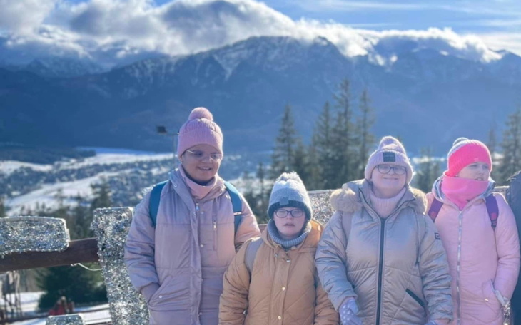 Czwórka dzieci na tle górskiego krajobrazu, uśmiechnięte i radosne.