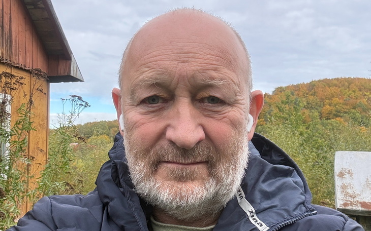 Portret mężczyzny na tle lasu, przedzierające się słońce.