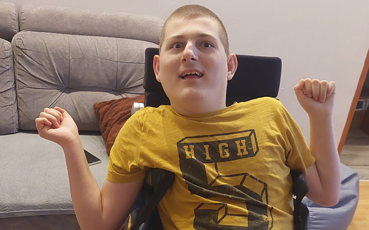 Chłopak na wózku inwalidzkim z uśmiechem na twarzy.