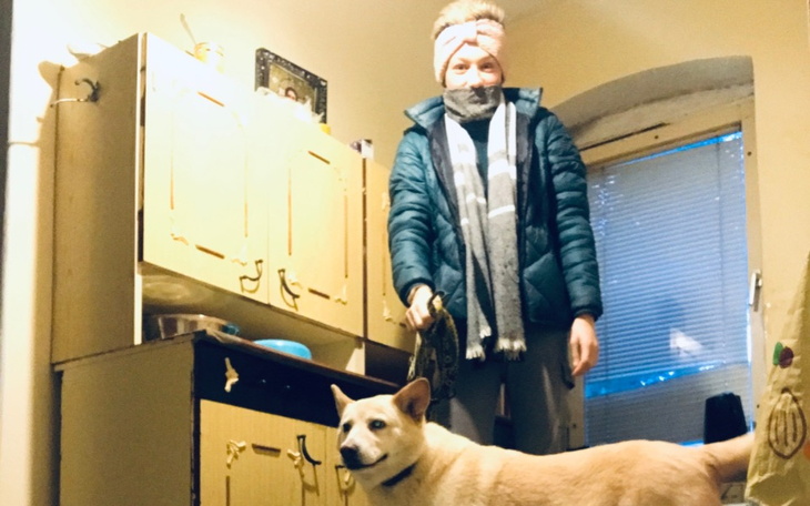 Osoba z psem w mieszkaniu, w zimowej odzieży.