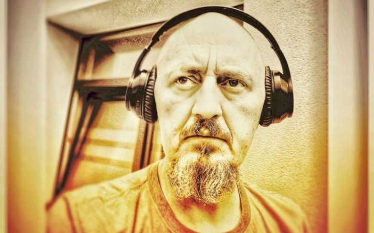 Mężczyzna w słuchawkach, z poważnym wyrazem twarzy.