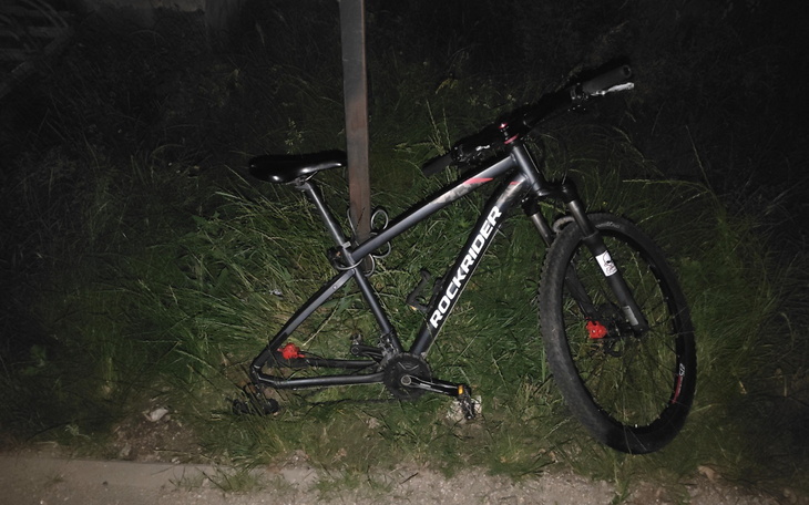 Rower górski zaparkowany w trawie, w nocy.