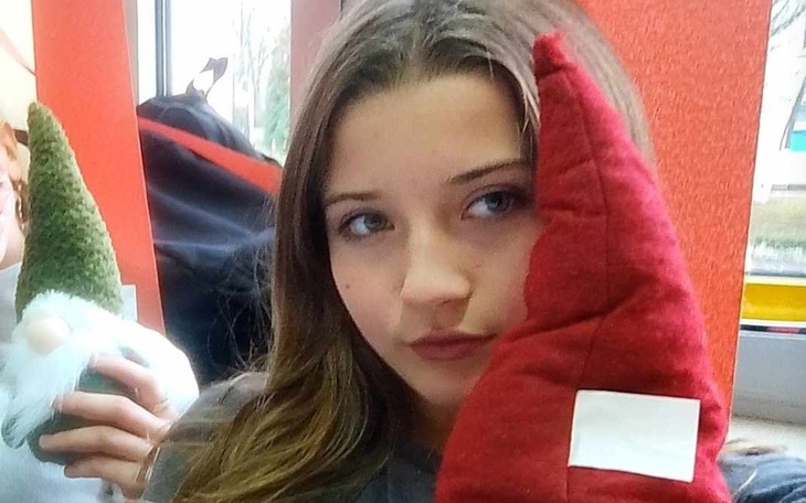 Młoda dziewczyna trzymająca w ręku czerwoną czapkę krasnala.