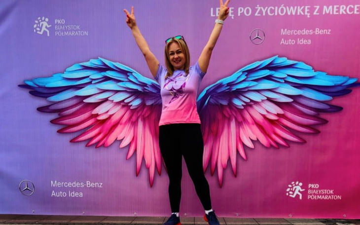 Kobieta z rękami w górze przed kolorowym tłem.