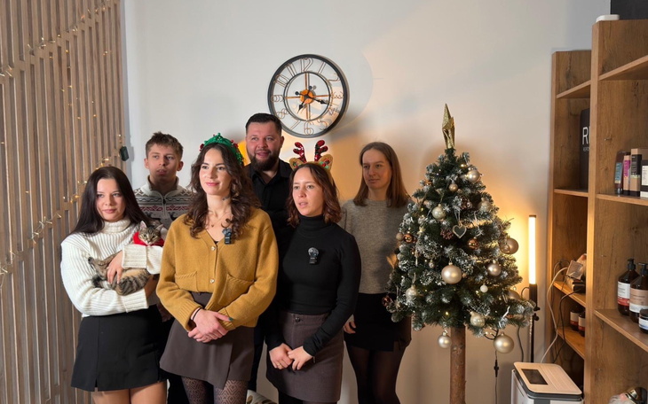 Grupa osób w świątecznych akcesoriach przy choince.