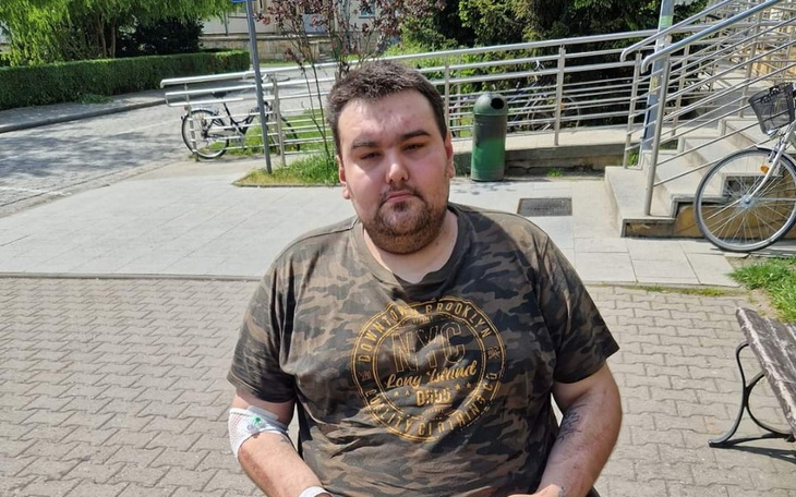 Mężczyzna siedzący na ławce, z opatrunkiem na ręce.