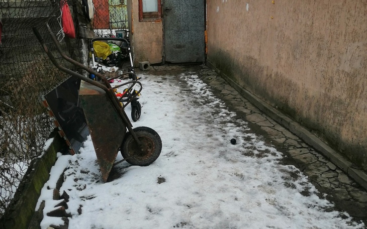 Zimowy widok na podwórko z wózkiem i narzędziami.
